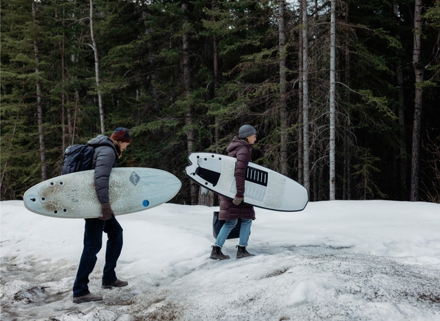 Two people walking with surfboards and crossfire jackets
